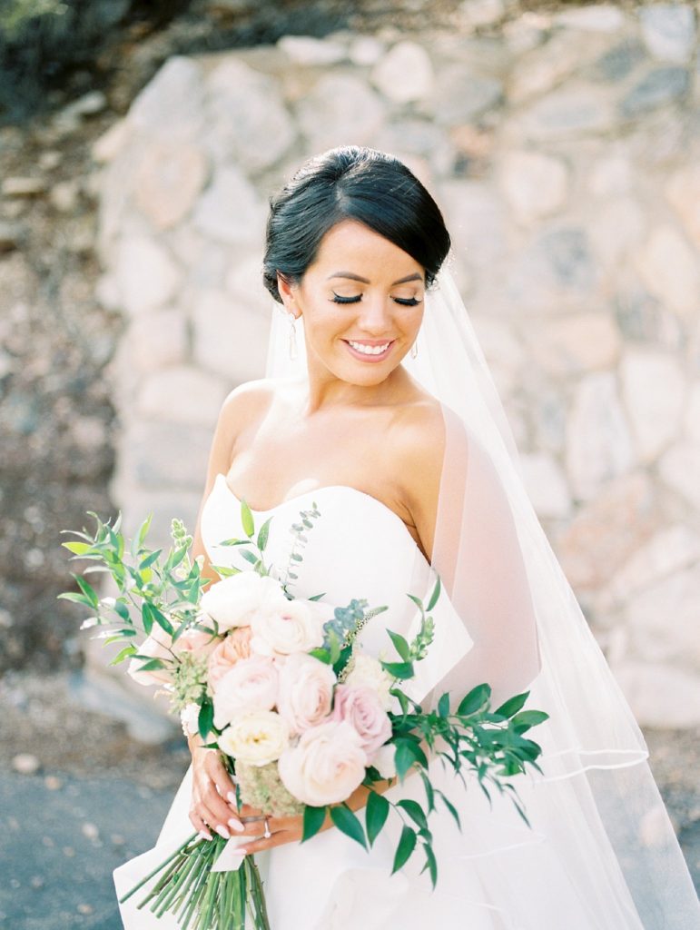 Bride with bouquet in front of stone wall